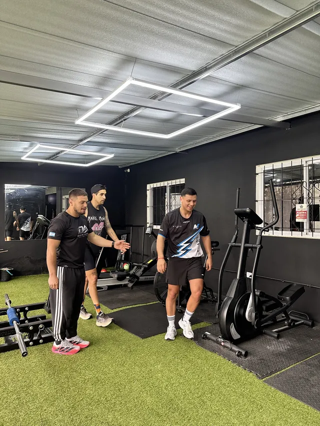 Dustin corrigiendo la técnica de dos alumnos en el gimnasio